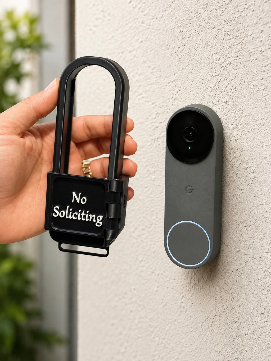 Hand holding the AvrenForge No Soliciting cover next to a Google Nest Doorbell for size comparison